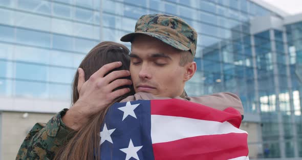 Soldier Hugging Girl Covered with American Flag.