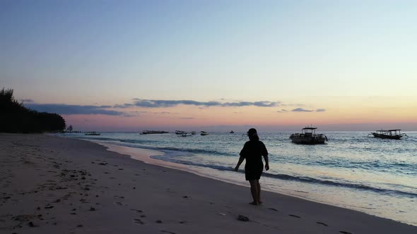 Lonely tourist girl walking around exotic beach of Seychelles at twilight, watching beautiful sky wi