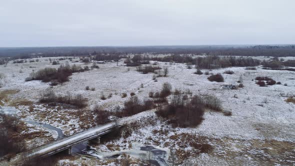 Flight Over the Winter Flat Landscape. A Bridge Over a Small River. Winter, Some Snow