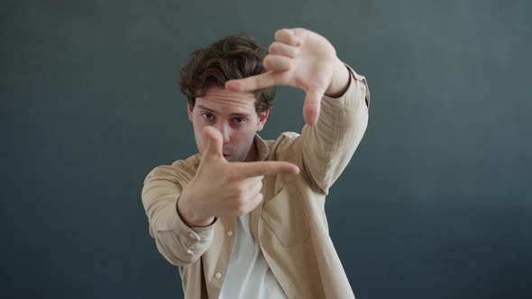 Portrait of Creative Man Looking at Camera Through Hands Frame Searching Beautiful View Then Winking