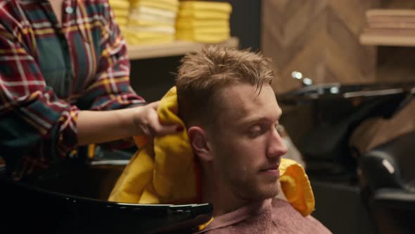 Barbershop: female barber washes the head of male client