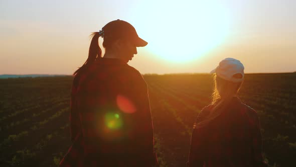 Young Mother Farmer Teaches Her Daughter To Work in a Wheat Field