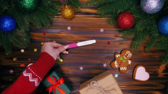 Hands puts positive pregnancy test on table as christmas present