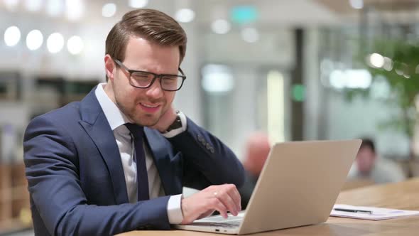 Businessman with Neck Pain Using Laptop at Work