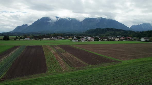 Aerial View of Green Agricultural Fields in Austria Near the Mountains in Clouds