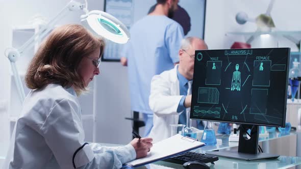 Woman Scientist Takes Notes on a Clipboard From a Computer Display