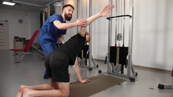 Physical Therapist Assisting Young Man in the Gym at Hospital