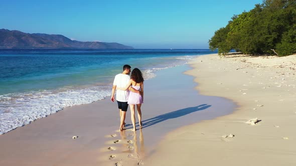 Romantic couple tanning on exotic resort beach wildlife by blue green sea and white sandy background