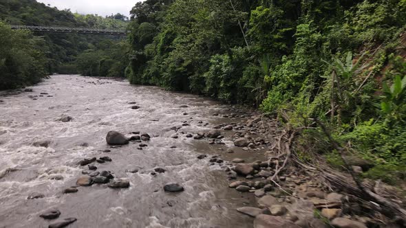 Low flying 4k aerial footage of a brown river flowing within by jungle dominated riverbanks. Rio Peñ