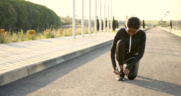 African American Fit Woman Tiying Shoelaces Outdoors