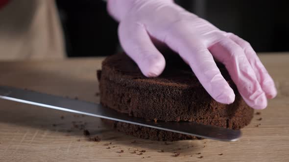 Pastry Chef is Cutting Chocolate Sponge Cake on Slices with Big Knife