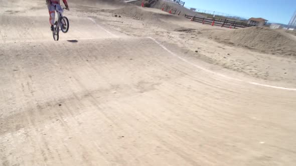 A young woman bmx rider riding bike on a dirt track.