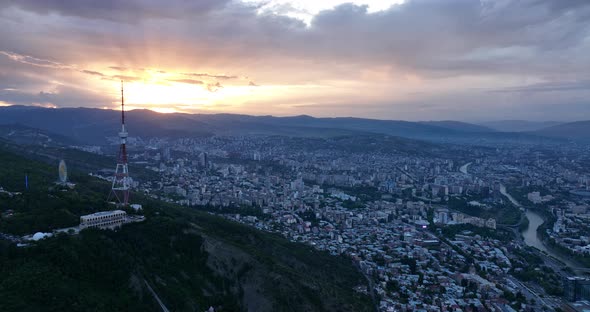 Aerial view of center of Tbilisi under Mtatsminda mountain at sunset. Georgia 2022 summer