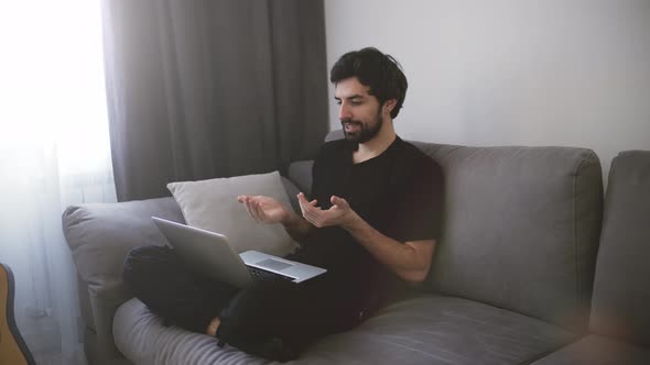 Man Sitting on Sofa and Making a Video Call Gesturing