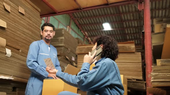 Two workers and colleagues check shipment orders stock at parcels warehouse.