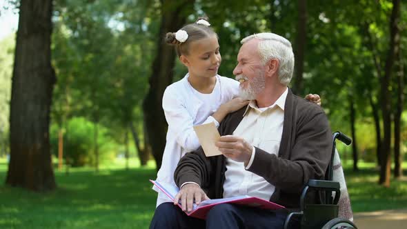 Handicapped Grandpa Showing to Granddaughter Family Photos Telling About Granny