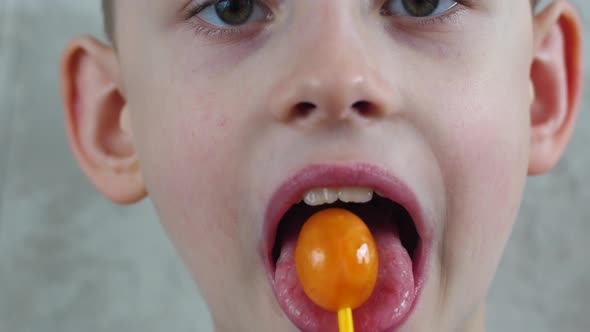 Portrait of a caucasian boy 7 years old with pleasure licking candy cane chups. The child sucks a sw