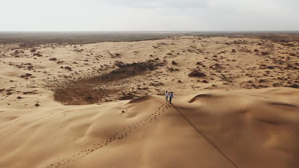 couple walking on sand dunes