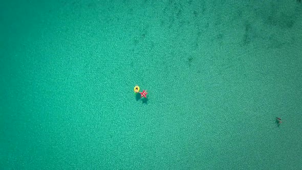 Aerial abstract view of two people floating in open sea on inflatables.