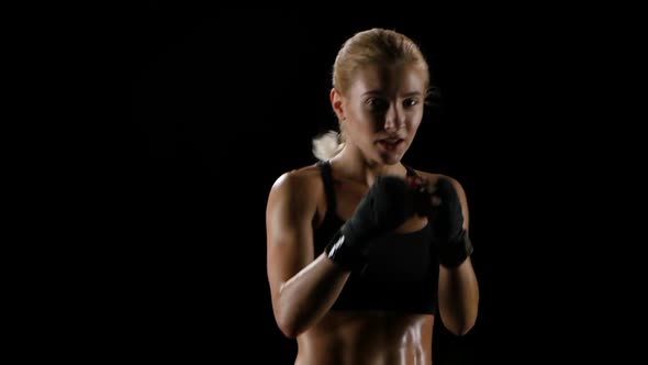 Slow Motion. Girl Boxer Training Herself in a Dark Studio