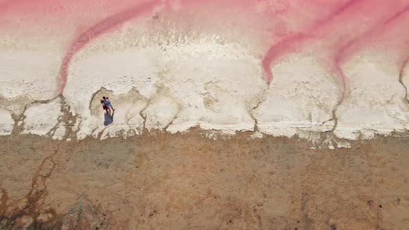 Drone Flight Over Pink Lake and Romantic Couple Standing on Lake Coast.