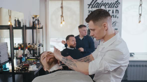 Barber Shaving Bearded Man Client in Barber Shop