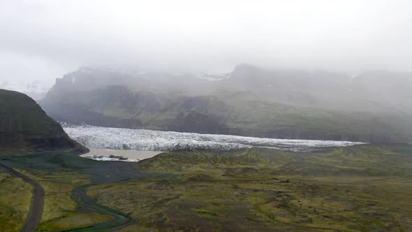 Iceland glacier wide shot with water and green grass with drone video moving forward.