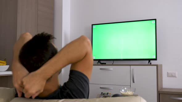 Man Watching a Big Green Mock-up Screen TV