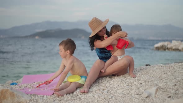 Mom with Children Playing with Toys on the Beach By the Sea