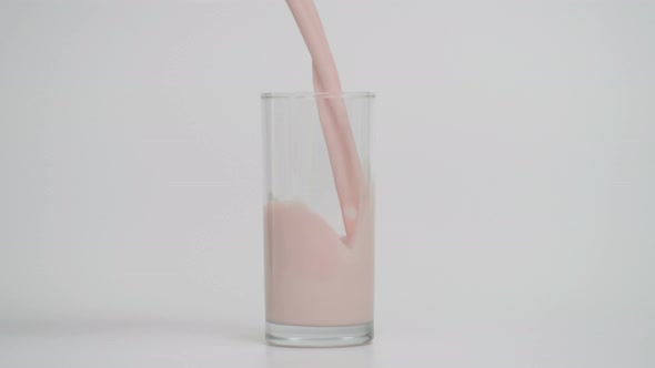 Slow Motion of Pouring Milk in Transparent Glass White Background