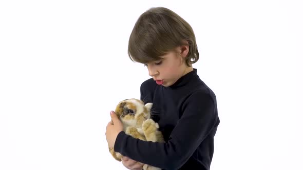 Brunet Boy Is Holding and Stroking Three Colored Rabbit at White Background. Slow Motion.