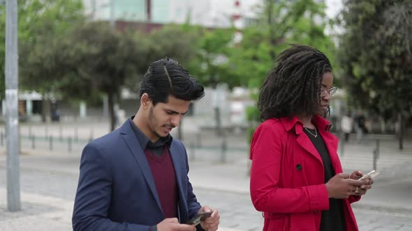 Afro-american Woman and Mixed-race Man Walking, Texting on Phone