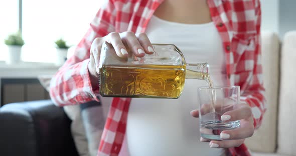 Pregnant Woman Pours Alcohol Into Glass Closeup