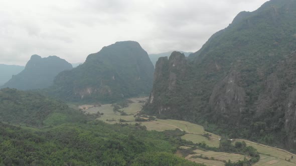 Aerial: flying over scenic cliffs rock pinnacles tropical jungle rice paddies