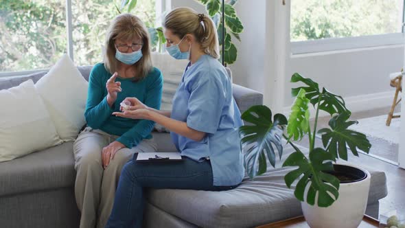 Female health worker showing medication doses to senior woman at home