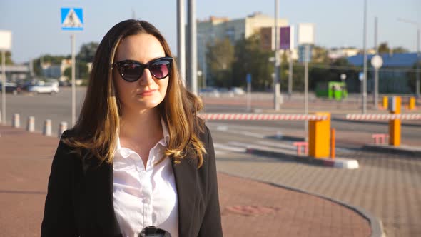 Portrait of Young Businesswoman with Cup of Coffee Walking Near Auto Parking at Sunny Day. Happy