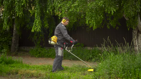 A Young Man From the Special Services Mows the Lawn with a Petrol Trimmer