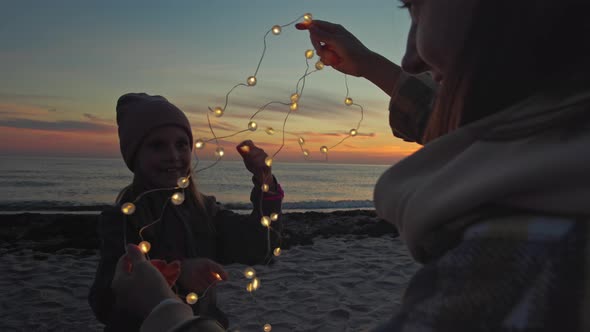 Woman with child celebrating on seaside at sunset