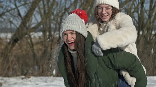 Mom and an Adult Daughter or Two Sisters are Having Fun During a Winter Walk and Someone is Throwing