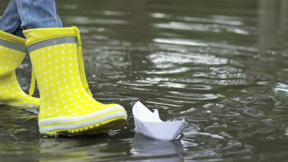 Kids in Rubber Boots Playing with Paper Boats