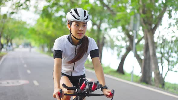 Asian active young sport beautiful woman riding bicycle exercise in the evening in public park.