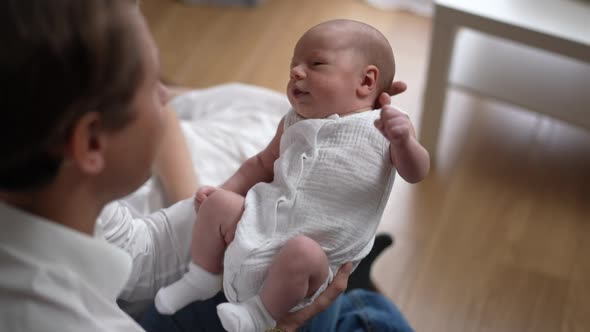 Newborn Caucasian Infant Shaking in Slow Motion in Hands of Happy Father Indoors at Home