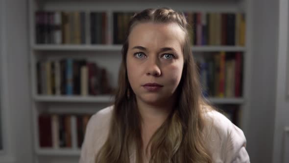 Woman Psychologist Nods and Agrees Portrait Against Background of Books