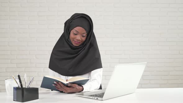 African Woman Turning Pages in Notebook