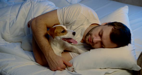 a Man Is Lying on His Side on a Sofa with White Linen in an Embrace with His Dog. the Guy Is Talking