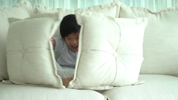 Cute Asian Child Playing Hide And Seek On Sofa