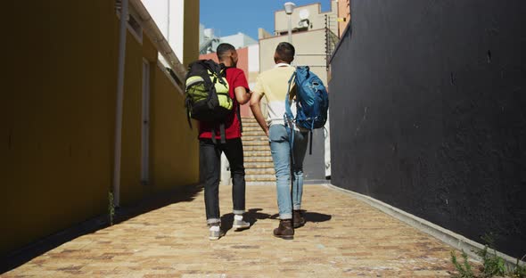 Back view of two mixed race male friends walking in the street