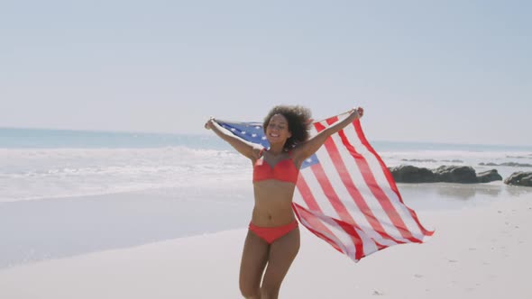 Young Mixed race woman dancing on the beach with the American flag