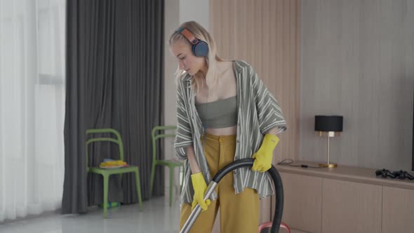 Young girl havig fun while cleaning floor with vacuum cleaner. 