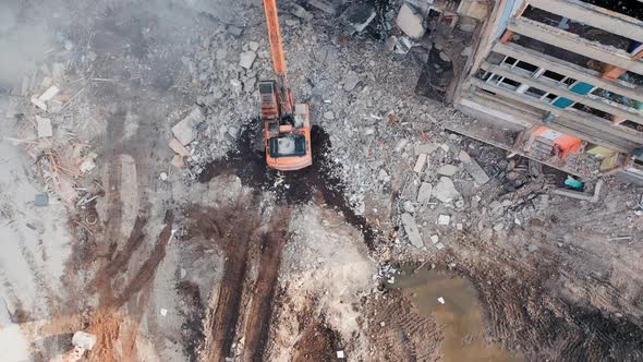Aerial view of excavator at a construction site destroys an old multi-storey building.